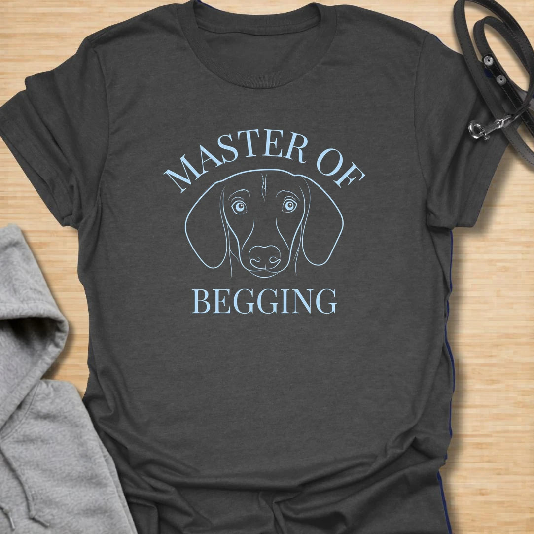Master Of Begging t-shirt for dachshund owners who know those big doxie eyes are impossible to resist. This simple line-art dachshund design is perfect for sausage dog lovers, dog moms, and anyone whose pup has perfected the art of asking for treats. A funny gift for pet parents who live with a professional snack negotiator.