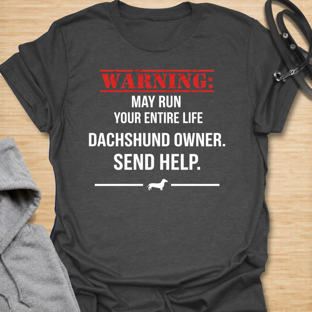 This Warning May Run Your Entire Life t-shirt is made for dachshund lovers who know their little long dog has completely taken over. Featuring bold warning-style typography, a small dachshund silhouette, and the phrase Dachshund Owner. Send Help., this design has a funny dog-parent feel that doxie owners will instantly understand. Perfect for dachshund moms, dachshund dads, wiener dog fans, rescue dog lovers, and anyone whose dachshund is absolutely in charge.