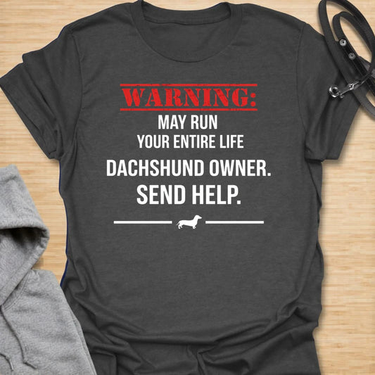 This Warning May Run Your Entire Life t-shirt is made for dachshund lovers who know their little long dog has completely taken over. Featuring bold warning-style typography, a small dachshund silhouette, and the phrase Dachshund Owner. Send Help., this design has a funny dog-parent feel that doxie owners will instantly understand. Perfect for dachshund moms, dachshund dads, wiener dog fans, rescue dog lovers, and anyone whose dachshund is absolutely in charge.
