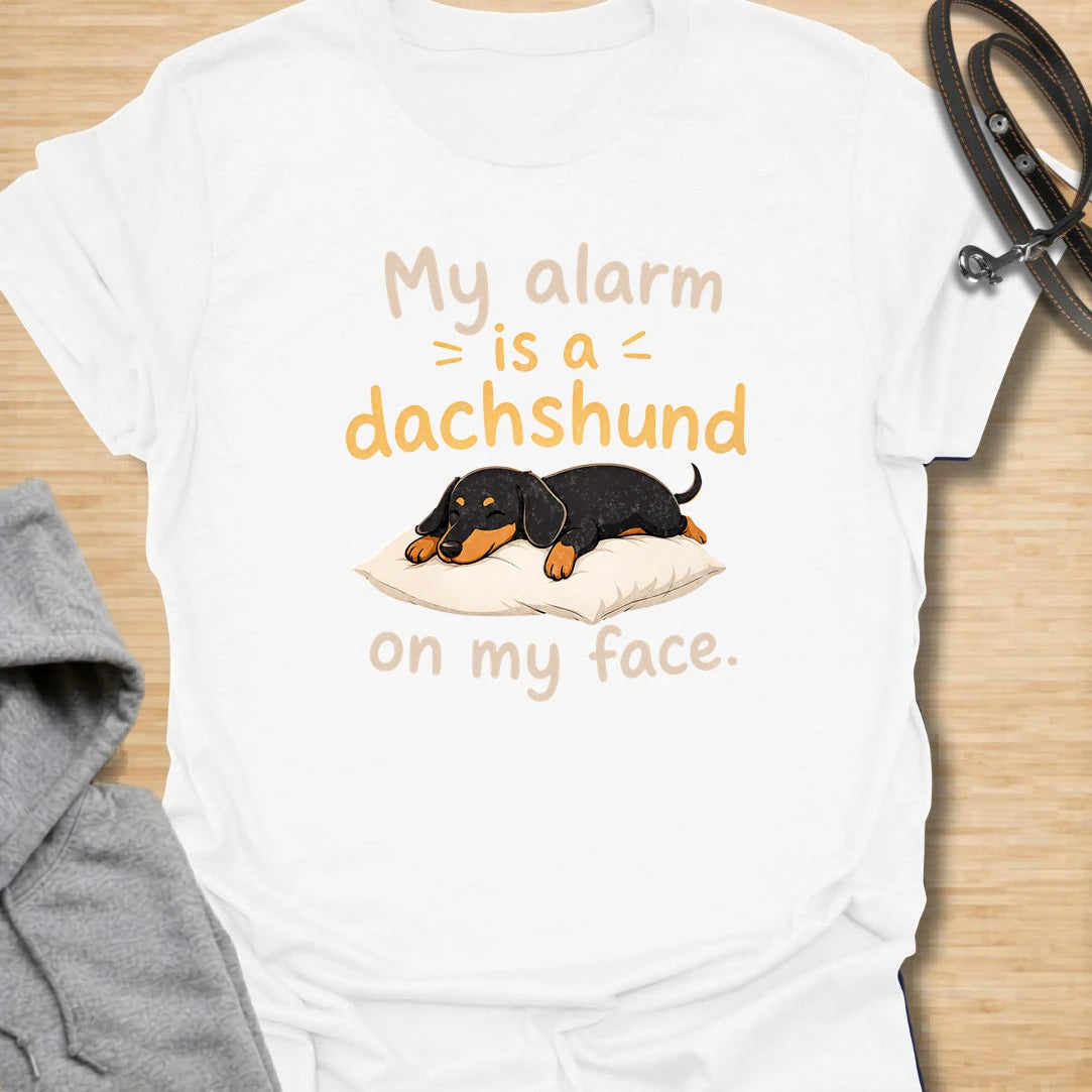 This My Alarm Is A Dachshund On My Face t-shirt is made for doxie lovers who know morning wake-up calls are not optional. Featuring a sleepy dachshund stretched across a pillow with playful text, this design has a cute and funny dog-parent feel. Perfect for dachshund moms, dachshund dads, wiener dog fans, rescue dog lovers, and anyone whose little long dog starts the day by climbing on their face.