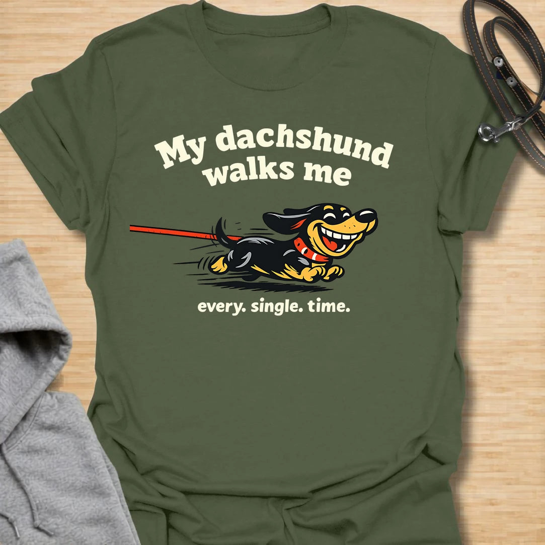 This My Dachshund Walks Me t-shirt is made for dachshund lovers who know who is really in charge of every walk. Featuring a happy running doxie pulling the leash with bold playful lettering and the phrase Every. Single. Time., this design has a funny chaotic dog-parent feel that wiener dog fans will instantly understand. Perfect for dachshund moms, dachshund dads, doxie owners, rescue dog lovers, and anyone whose tiny-legged dog sets the pace.