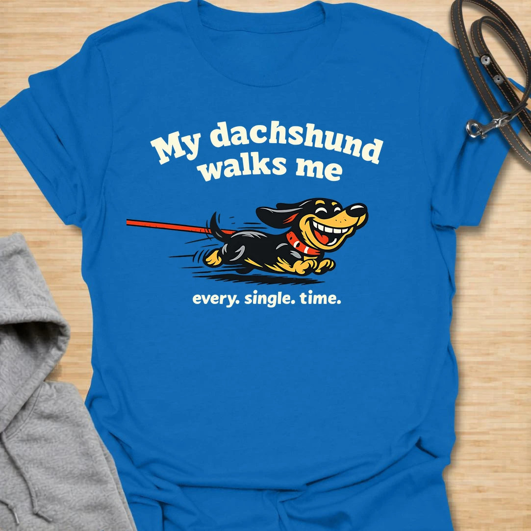 This My Dachshund Walks Me t-shirt is made for dachshund lovers who know who is really in charge of every walk. Featuring a happy running doxie pulling the leash with bold playful lettering and the phrase Every. Single. Time., this design has a funny chaotic dog-parent feel that wiener dog fans will instantly understand. Perfect for dachshund moms, dachshund dads, doxie owners, rescue dog lovers, and anyone whose tiny-legged dog sets the pace.