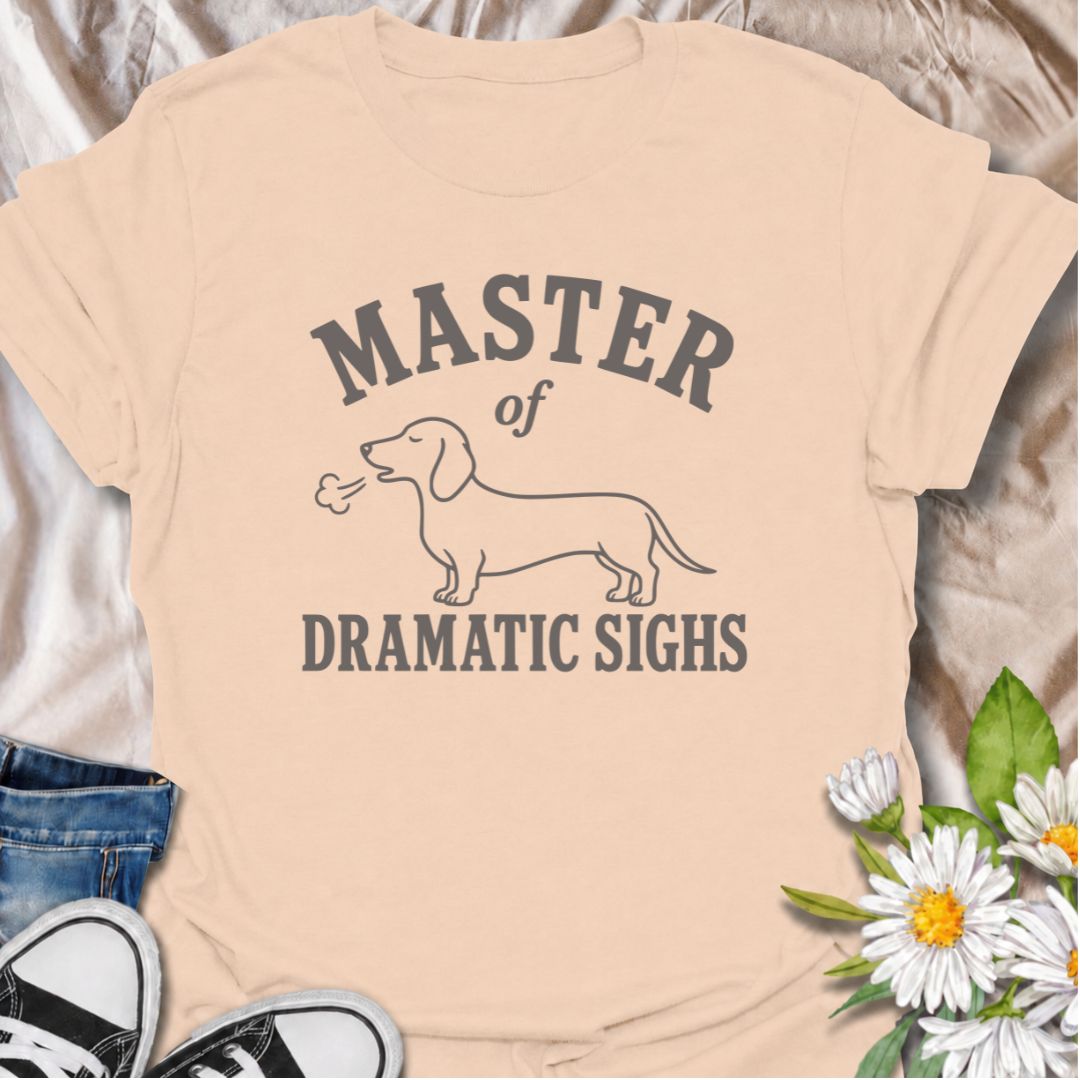 For the dachshund who turns every minor inconvenience into a full performance. This funny dachshund T-shirt features a simple sausage dog illustration with the phrase “Master of Dramatic Sighs.” A playful, easy-to-wear gift for dachshund owners, dog moms, dog dads, and anyone familiar with classic doxie drama.