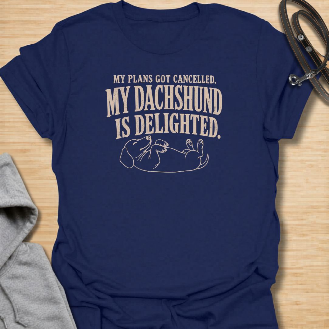 This My Plans Got Canceled My Dachshund Is Delighted t-shirt is made for doxie lovers who know their little long dog is happiest when everyone stays home. Featuring bold vintage-style typography and a relaxed dachshund lying on its back, this design has a funny, relatable dog-parent feel that wiener dog fans will instantly understand. Perfect for dachshund moms, dachshund dads, rescue dog lovers, introverts, and anyone whose dachshund fully supports canceled plans.