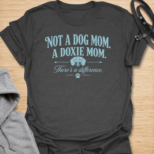 This Not A Dog Mom A Doxie Mom t-shirt is made for dachshund lovers who know there is definitely a difference. Featuring vintage-style typography, a small dachshund accent, paw print details, and a funny breed-specific message, this design has a simple dog-parent feel that doxie owners will instantly understand. Perfect for dachshund moms, wiener dog fans, sausage dog lovers, rescue dog owners, and anyone proudly living the doxie mom life.