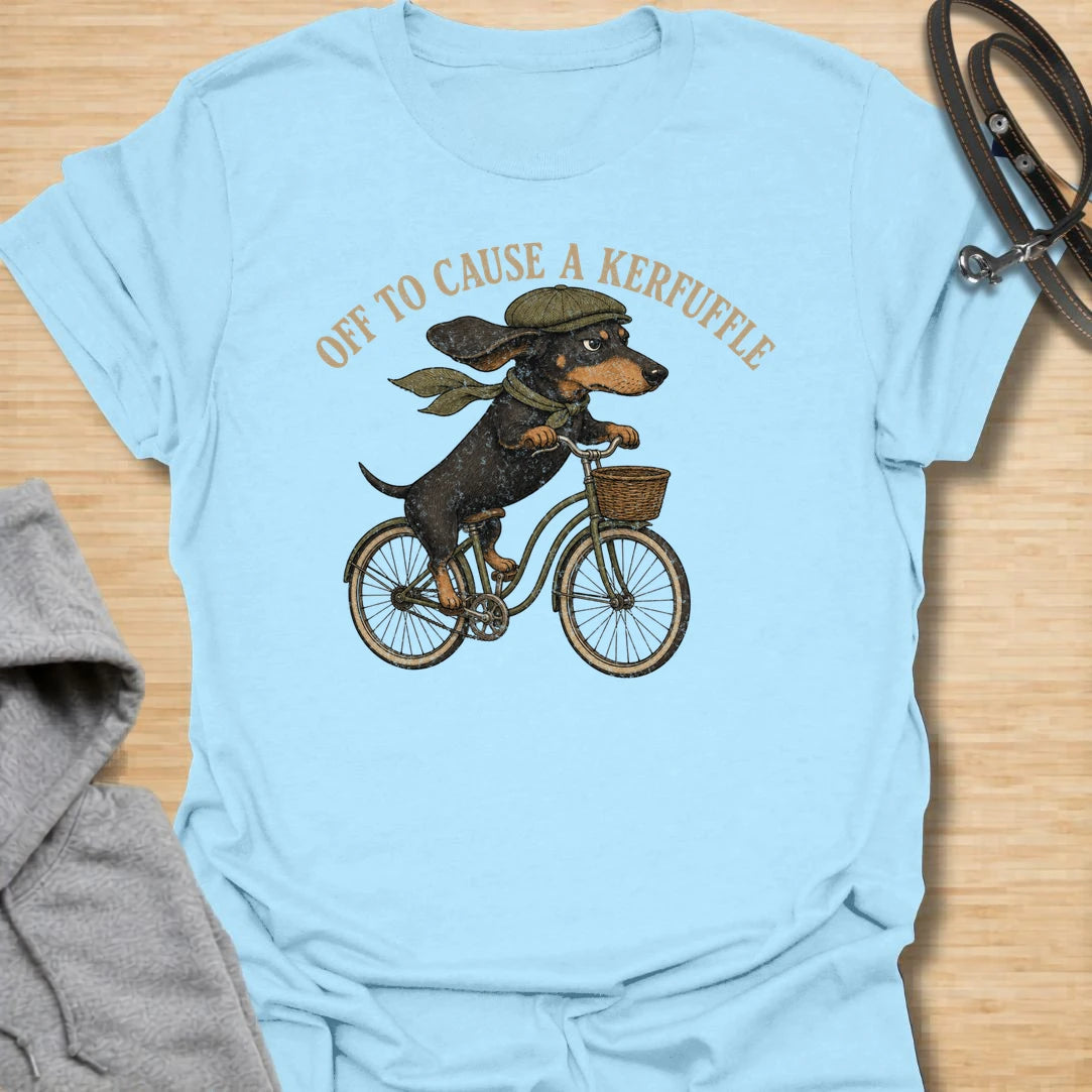 This Off To Cause A Kerfuffle t-shirt is made for dachshund lovers who know their little long dog is always headed somewhere to create a situation. Featuring a determined dachshund riding a vintage bike with flying ears and classic muted colors, this design has a funny chaotic dog-parent feel. Perfect for dachshund moms, dachshund dads, wiener dog fans, rescue dog lovers, and anyone whose doxie is always on a mission.