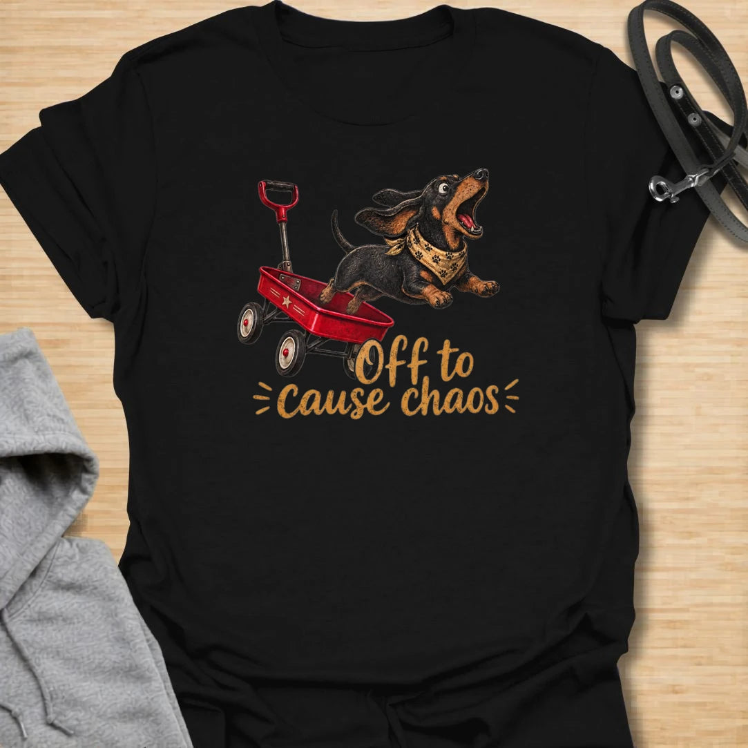 This Off To Cause Chaos t-shirt is made for dachshund lovers who know their little long dog is always ready for nonsense. Featuring a black and tan dachshund launching from a red wagon with a bandana and excited expression, this design has a fun action-filled dog-parent feel. Perfect for dachshund moms, dachshund dads, wiener dog fans, rescue dog lovers, and anyone whose doxie brings the chaos everywhere.