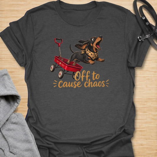 This Off To Cause Chaos t-shirt is made for dachshund lovers who know their little long dog is always ready for nonsense. Featuring a black and tan dachshund launching from a red wagon with a bandana and excited expression, this design has a fun action-filled dog-parent feel. Perfect for dachshund moms, dachshund dads, wiener dog fans, rescue dog lovers, and anyone whose doxie brings the chaos everywhere.