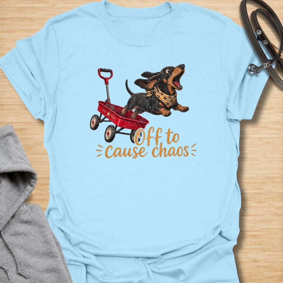 This Off To Cause Chaos t-shirt is made for dachshund lovers who know their little long dog is always ready for nonsense. Featuring a black and tan dachshund launching from a red wagon with a bandana and excited expression, this design has a fun action-filled dog-parent feel. Perfect for dachshund moms, dachshund dads, wiener dog fans, rescue dog lovers, and anyone whose doxie brings the chaos everywhere.