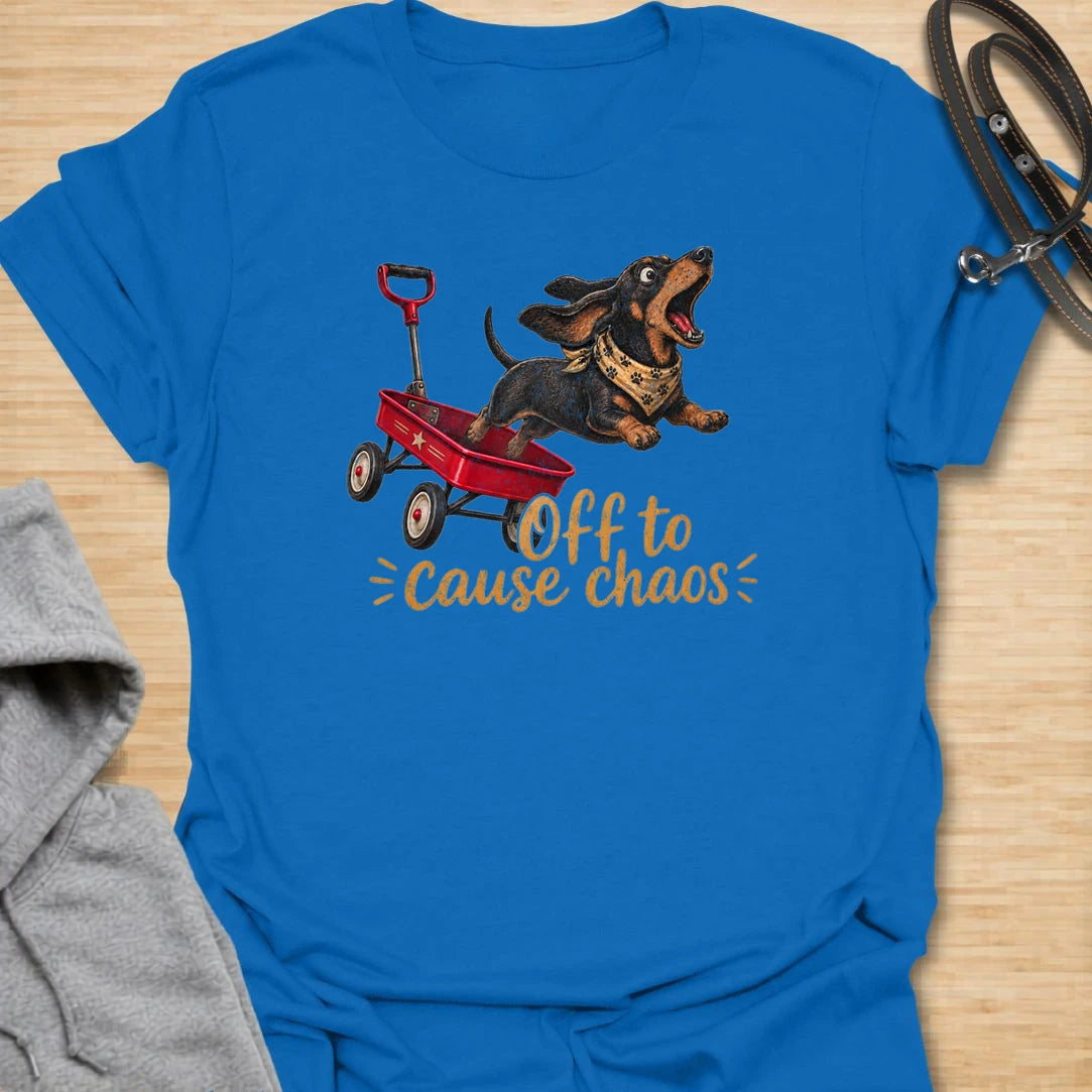 This Off To Cause Chaos t-shirt is made for dachshund lovers who know their little long dog is always ready for nonsense. Featuring a black and tan dachshund launching from a red wagon with a bandana and excited expression, this design has a fun action-filled dog-parent feel. Perfect for dachshund moms, dachshund dads, wiener dog fans, rescue dog lovers, and anyone whose doxie brings the chaos everywhere.
