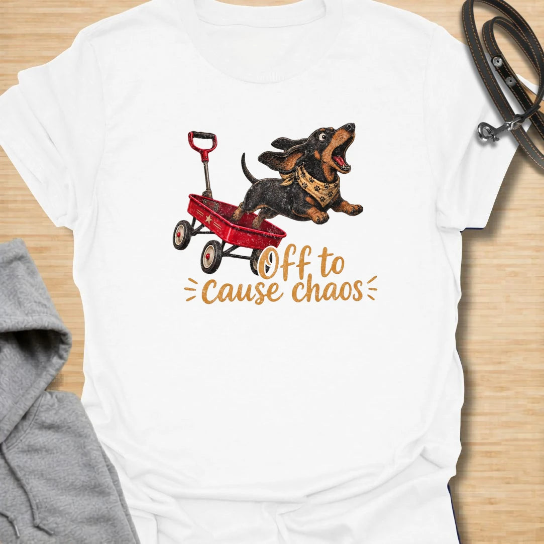 This Off To Cause Chaos t-shirt is made for dachshund lovers who know their little long dog is always ready for nonsense. Featuring a black and tan dachshund launching from a red wagon with a bandana and excited expression, this design has a fun action-filled dog-parent feel. Perfect for dachshund moms, dachshund dads, wiener dog fans, rescue dog lovers, and anyone whose doxie brings the chaos everywhere.