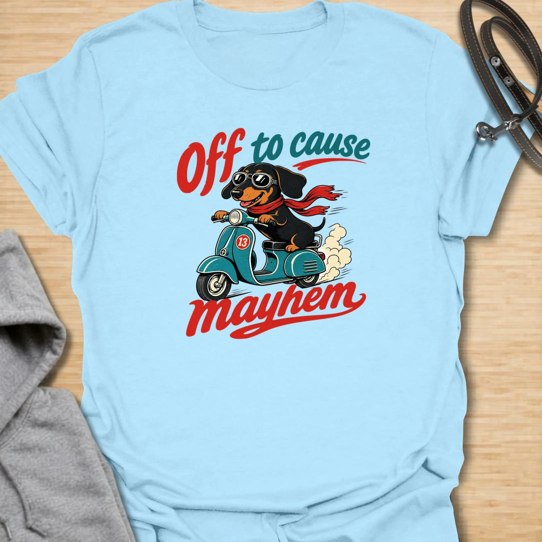 Off To Cause Mayhem t-shirt for dachshund lovers who know their doxie is always ready for mischief, speed, and drama. This funny design features a black and tan dachshund riding a scooter with sunglasses, a red scarf, and bold retro text. Perfect for sausage dog fans, doxie moms, and anyone who loves chaotic little dogs with big personalities.