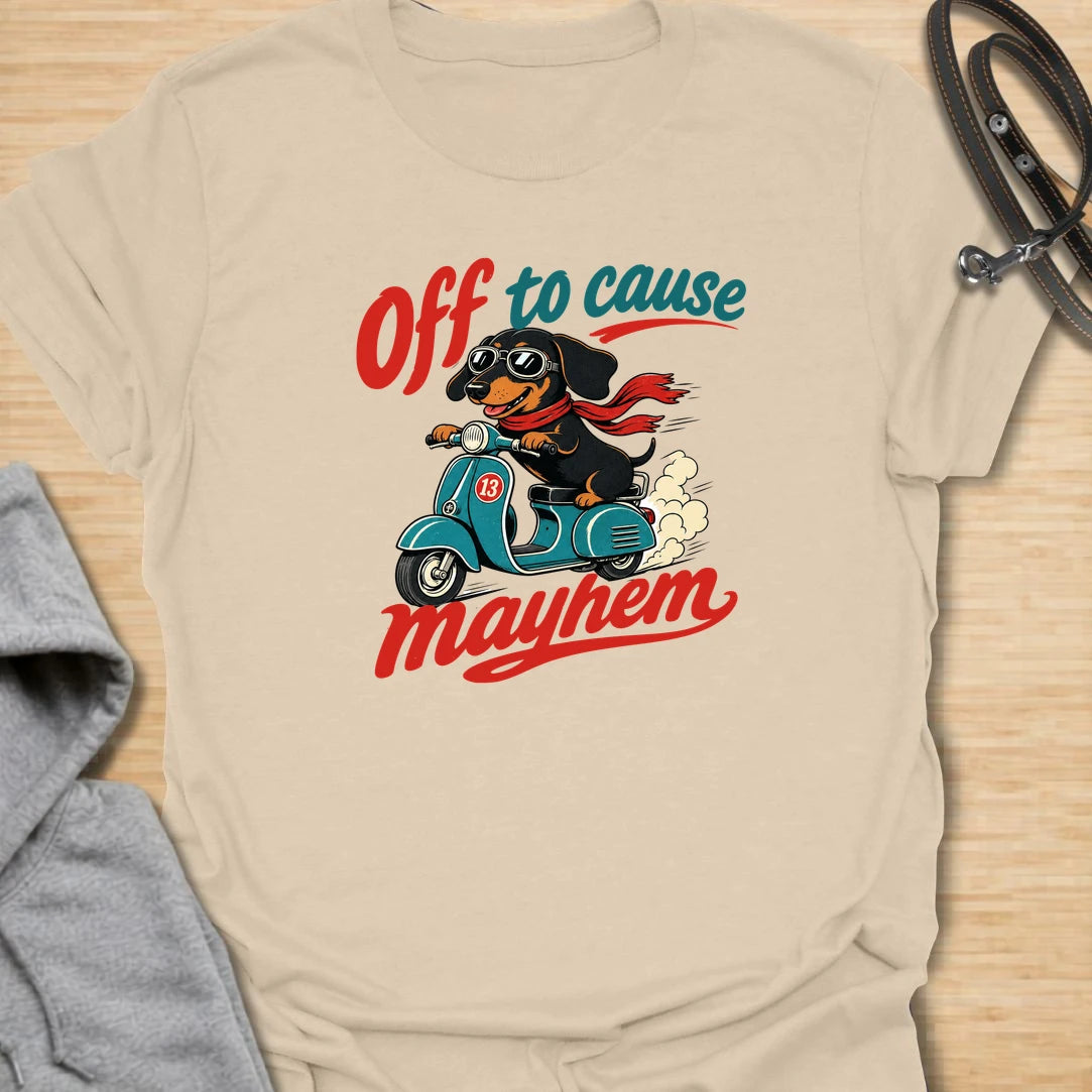 Off To Cause Mayhem t-shirt for dachshund lovers who know their doxie is always ready for mischief, speed, and drama. This funny design features a black and tan dachshund riding a scooter with sunglasses, a red scarf, and bold retro text. Perfect for sausage dog fans, doxie moms, and anyone who loves chaotic little dogs with big personalities.