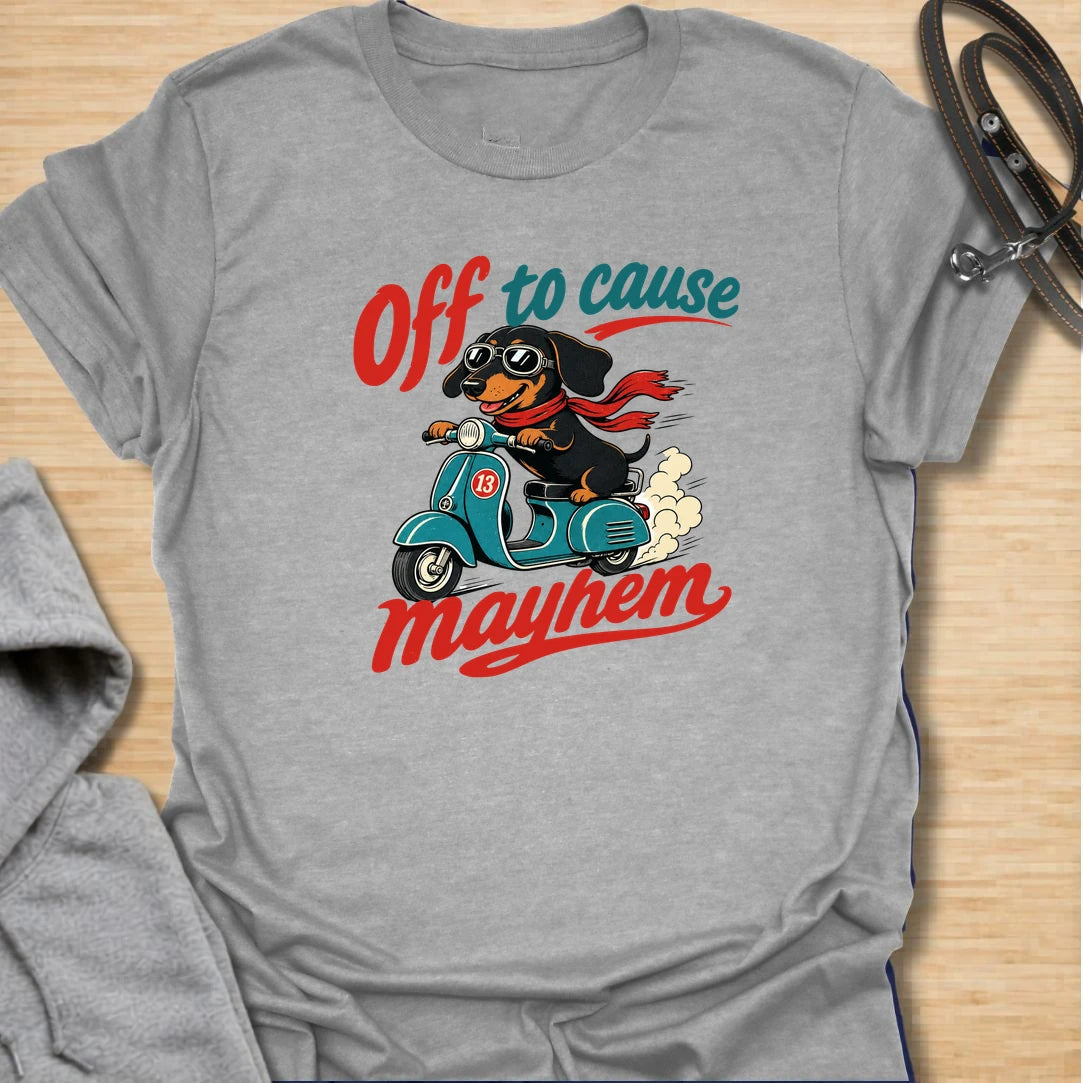 Off To Cause Mayhem t-shirt for dachshund lovers who know their doxie is always ready for mischief, speed, and drama. This funny design features a black and tan dachshund riding a scooter with sunglasses, a red scarf, and bold retro text. Perfect for sausage dog fans, doxie moms, and anyone who loves chaotic little dogs with big personalities.