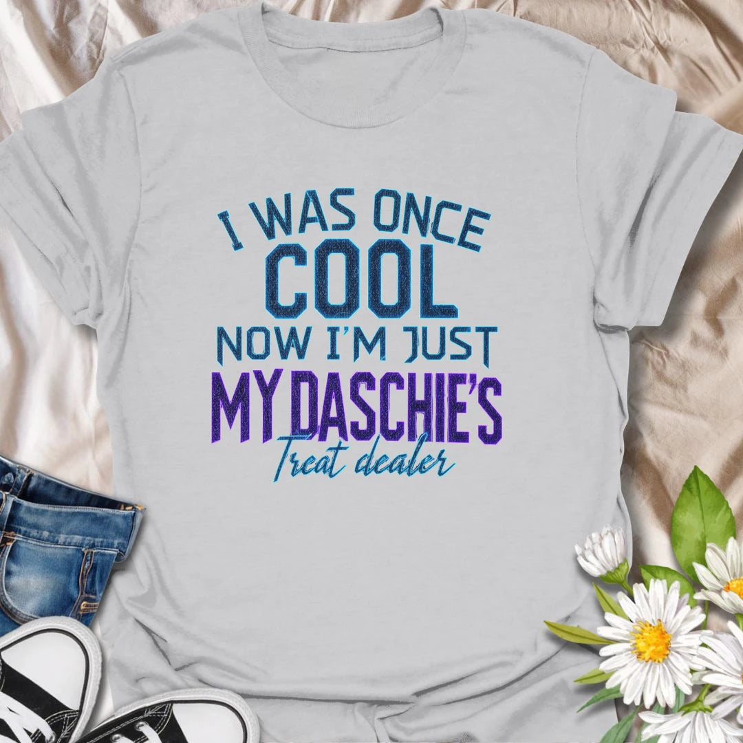 Life changes when a dachshund appoints you as the official treat dealer. This funny dachshund T-shirt is perfect for devoted daschie/doxie/daxie owners who know every snack request is urgent. A playful gift for dachshund moms, dads, and sausage dog lovers.