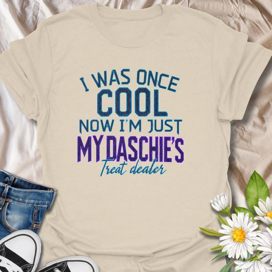 Life changes when a dachshund appoints you as the official treat dealer. This funny dachshund T-shirt is perfect for devoted daschie/doxie/daxie owners who know every snack request is urgent. A playful gift for dachshund moms, dads, and sausage dog lovers.
