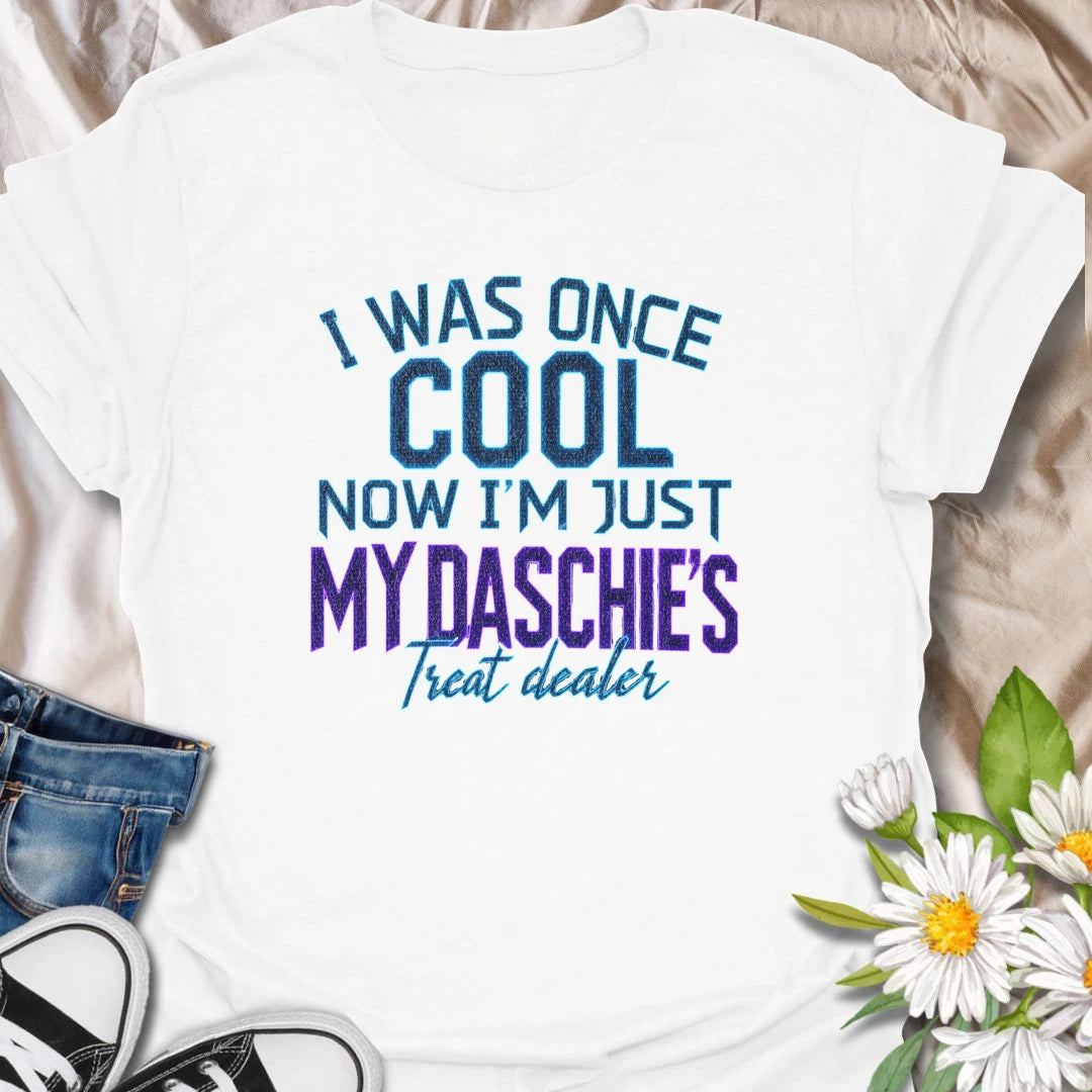 Life changes when a dachshund appoints you as the official treat dealer. This funny dachshund T-shirt is perfect for devoted daschie/doxie/daxie owners who know every snack request is urgent. A playful gift for dachshund moms, dads, and sausage dog lovers.