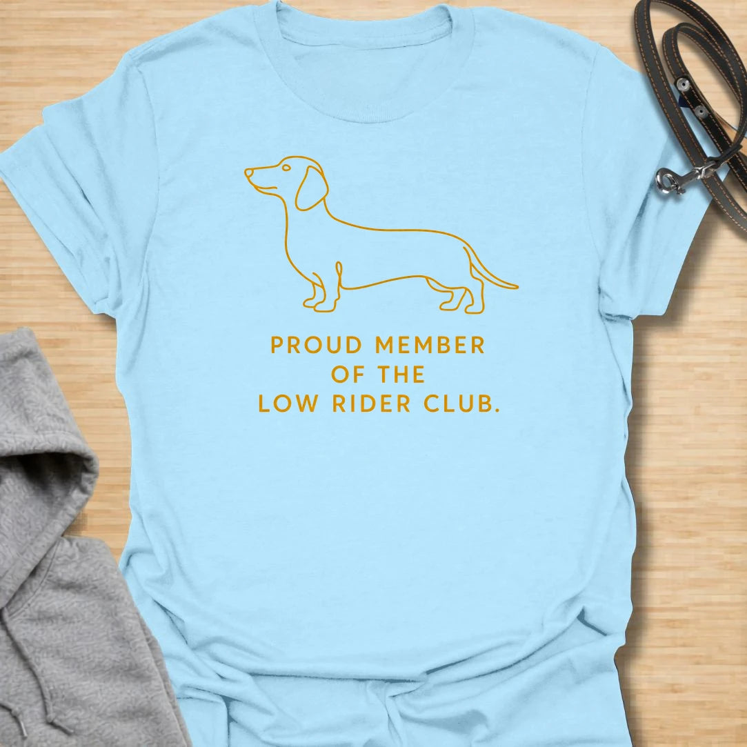 This Proud Member Of The Low Rider Club t-shirt is made for dachshund lovers who celebrate tiny legs, long bodies, and big personality. Featuring a simple dachshund line illustration with bold club-style lettering, this design has a clean, classic dog-parent feel. Perfect for dachshund moms, dachshund dads, wiener dog fans, rescue dog lovers, and anyone proudly part of the low rider club.