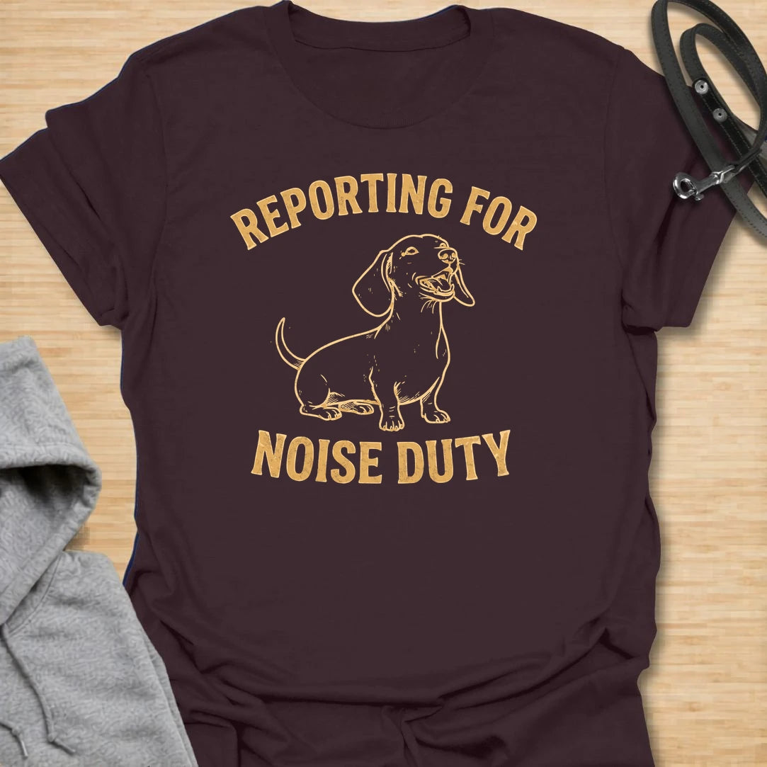 This Reporting For Noise Duty t-shirt is made for dachshund lovers who know their little long dog takes barking very seriously. Featuring a bold one-color dachshund illustration with strong simple lettering, this design has a funny breed-specific feel that doxie owners will instantly understand. Perfect for dachshund moms, dachshund dads, wiener dog fans, rescue dog lovers, and anyone living with a tiny self-appointed alarm system.