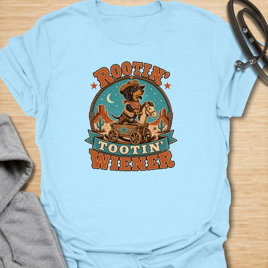 Rootin Tootin Wiener t-shirt for dachshund lovers who enjoy funny western dog humor and chaotic sausage dog energy. This playful design features a cowboy-style dachshund riding in a wagon with bold vintage rodeo lettering. Perfect for doxie moms, wiener dog fans, sausage dog owners, and anyone who loves a small dog with big outlaw attitude.