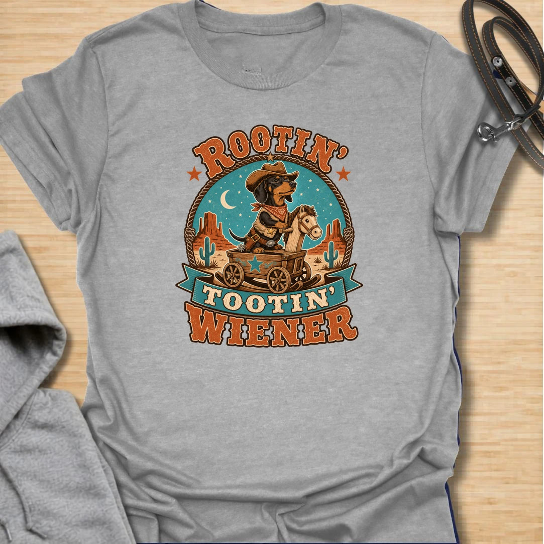 Rootin Tootin Wiener t-shirt for dachshund lovers who enjoy funny western dog humor and chaotic sausage dog energy. This playful design features a cowboy-style dachshund riding in a wagon with bold vintage rodeo lettering. Perfect for doxie moms, wiener dog fans, sausage dog owners, and anyone who loves a small dog with big outlaw attitude.