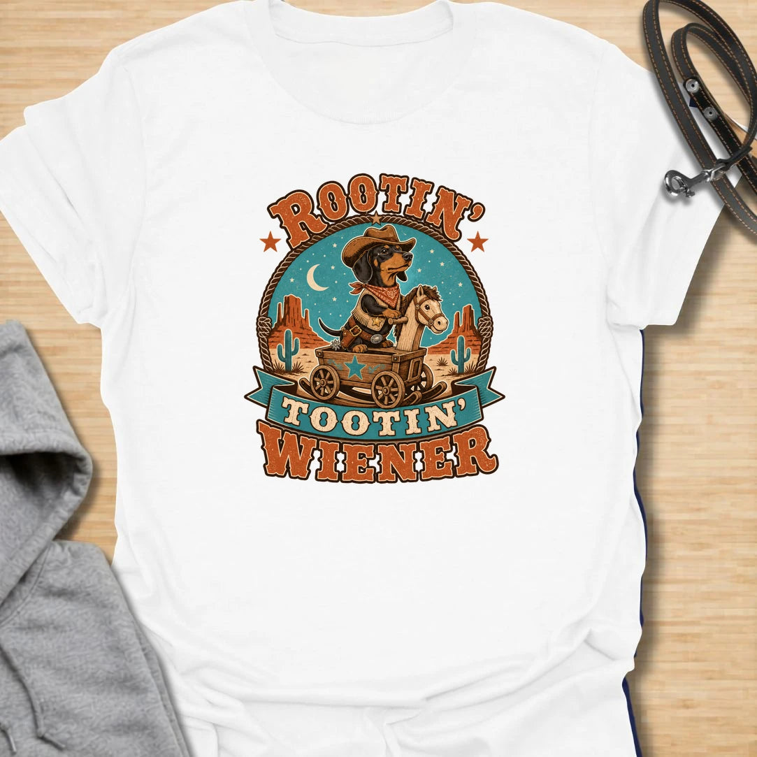 Rootin Tootin Wiener t-shirt for dachshund lovers who enjoy funny western dog humor and chaotic sausage dog energy. This playful design features a cowboy-style dachshund riding in a wagon with bold vintage rodeo lettering. Perfect for doxie moms, wiener dog fans, sausage dog owners, and anyone who loves a small dog with big outlaw attitude.