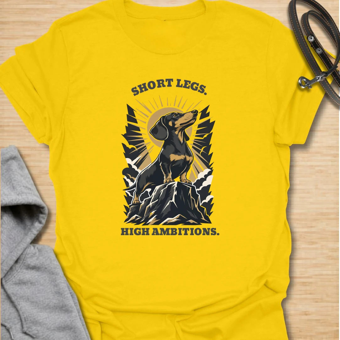 Short Legs High Ambitions t-shirt for dachshund lovers who know tiny legs never mean tiny confidence. This bold mountain-style design features a proud dachshund standing tall with dramatic vintage outdoor energy. A great gift for dachshund moms, dachshund dads, hikers, dog lovers, and anyone who loves a determined little sausage dog. Perfect for everyday wear, dog walks, casual weekends, or showing off big doxie attitude.