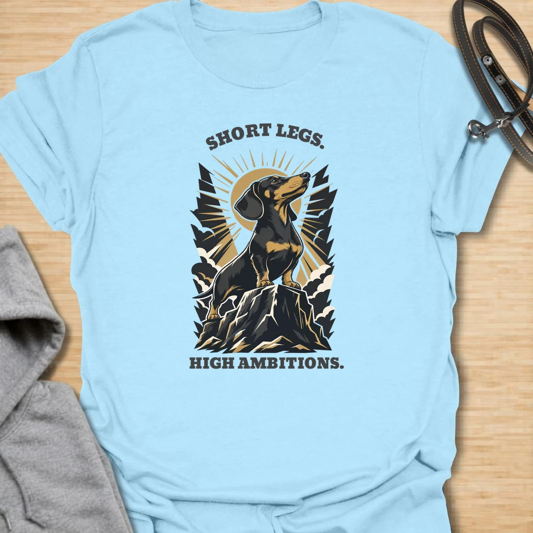 Short Legs High Ambitions t-shirt for dachshund lovers who know tiny legs never mean tiny confidence. This bold mountain-style design features a proud dachshund standing tall with dramatic vintage outdoor energy. A great gift for dachshund moms, dachshund dads, hikers, dog lovers, and anyone who loves a determined little sausage dog. Perfect for everyday wear, dog walks, casual weekends, or showing off big doxie attitude.
