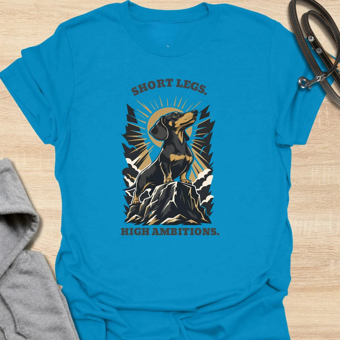 Short Legs High Ambitions t-shirt for dachshund lovers who know tiny legs never mean tiny confidence. This bold mountain-style design features a proud dachshund standing tall with dramatic vintage outdoor energy. A great gift for dachshund moms, dachshund dads, hikers, dog lovers, and anyone who loves a determined little sausage dog. Perfect for everyday wear, dog walks, casual weekends, or showing off big doxie attitude.