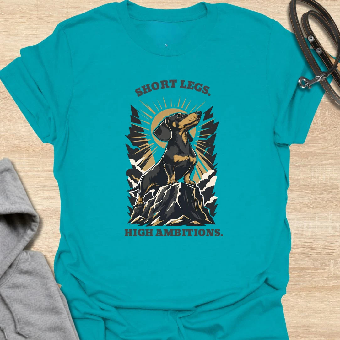Short Legs High Ambitions t-shirt for dachshund lovers who know tiny legs never mean tiny confidence. This bold mountain-style design features a proud dachshund standing tall with dramatic vintage outdoor energy. A great gift for dachshund moms, dachshund dads, hikers, dog lovers, and anyone who loves a determined little sausage dog. Perfect for everyday wear, dog walks, casual weekends, or showing off big doxie attitude.