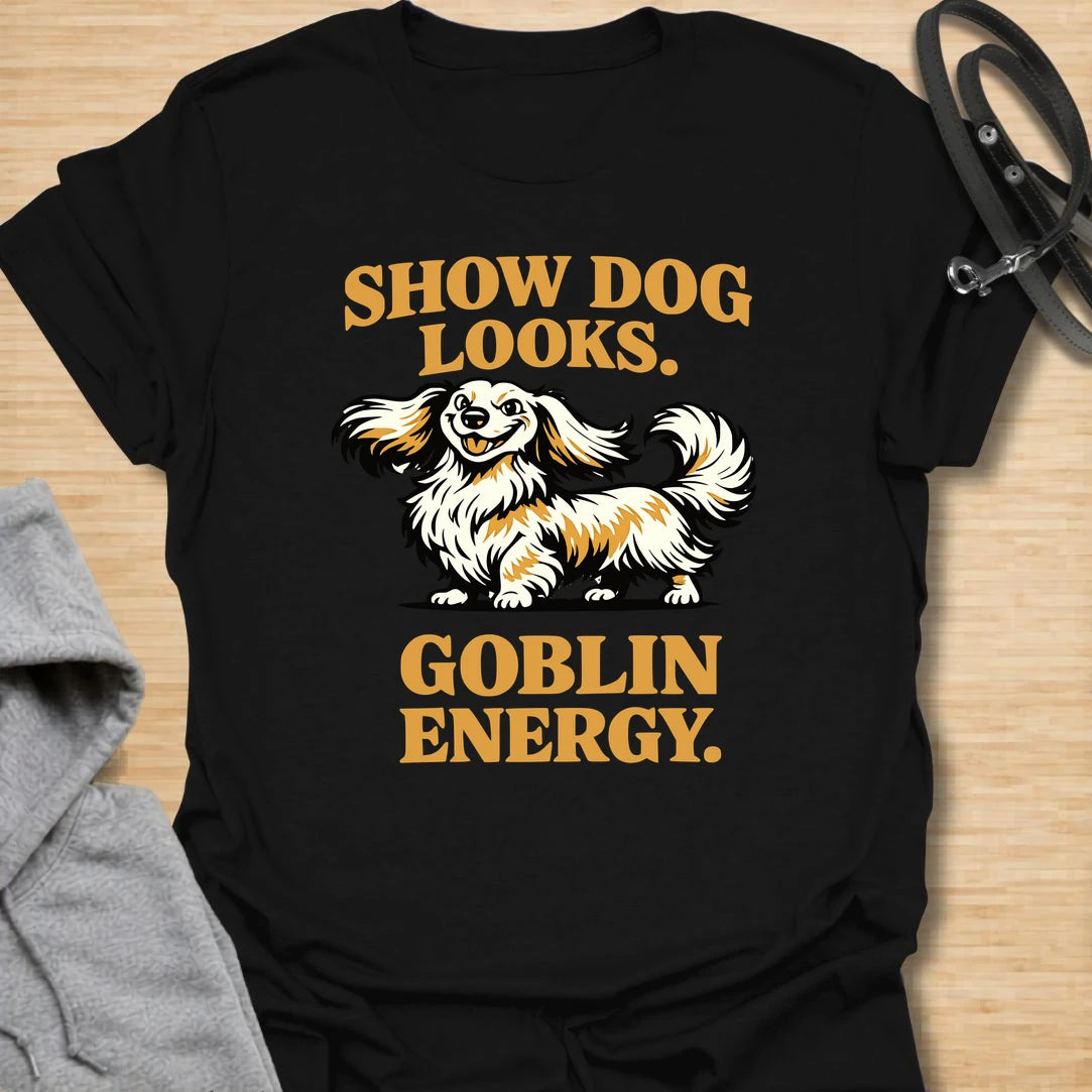 This Show Dog Looks Goblin Energy t-shirt is made for long-haired dachshund lovers who know their elegant little dog can look polished and still act completely unhinged. Featuring a fluffy long-haired doxie with bold retro lettering, this design has a funny breed-specific feel that dachshund owners will instantly understand. Perfect for dachshund moms, dachshund dads, long-haired doxie fans, rescue dog lovers, and anyone whose pretty dog has pure goblin energy.