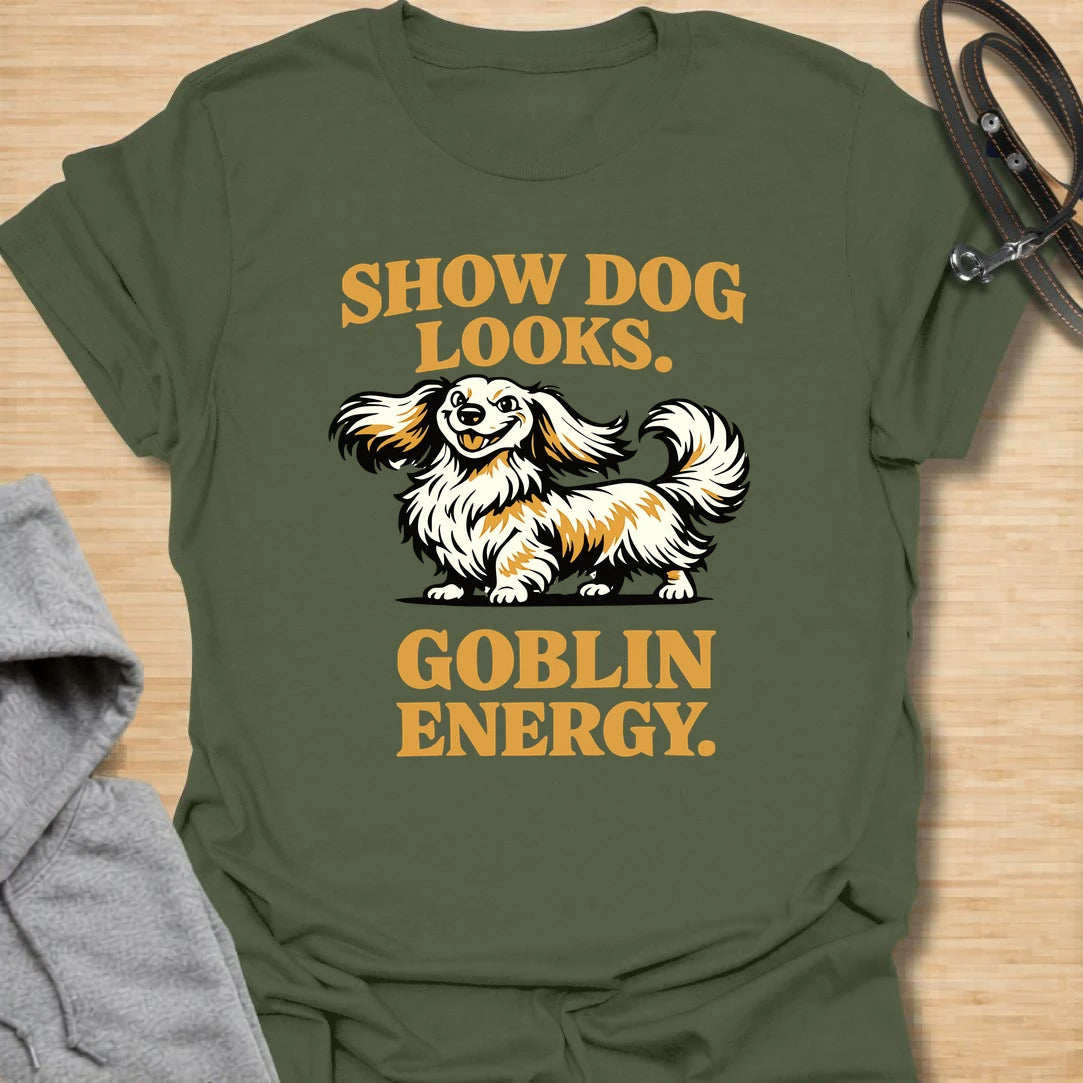 This Show Dog Looks Goblin Energy t-shirt is made for long-haired dachshund lovers who know their elegant little dog can look polished and still act completely unhinged. Featuring a fluffy long-haired doxie with bold retro lettering, this design has a funny breed-specific feel that dachshund owners will instantly understand. Perfect for dachshund moms, dachshund dads, long-haired doxie fans, rescue dog lovers, and anyone whose pretty dog has pure goblin energy.