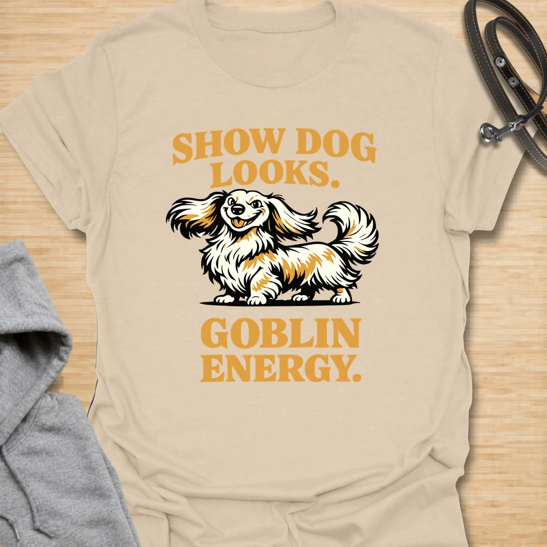 This Show Dog Looks Goblin Energy t-shirt is made for long-haired dachshund lovers who know their elegant little dog can look polished and still act completely unhinged. Featuring a fluffy long-haired doxie with bold retro lettering, this design has a funny breed-specific feel that dachshund owners will instantly understand. Perfect for dachshund moms, dachshund dads, long-haired doxie fans, rescue dog lovers, and anyone whose pretty dog has pure goblin energy.