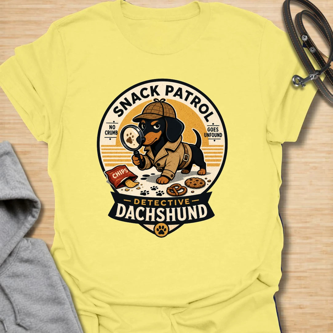 Snack Patrol Detective Dachshund t-shirt for the doxie who is always first on the scene when food appears. This funny badge-style design features a dachshund detective theme with snack details and retro lettering. It is perfect for dachshund owners whose dog monitors every bite, crumb, and kitchen sound. A great gift for wiener dog lovers, sausage dog fans, and food-motivated dog households.
