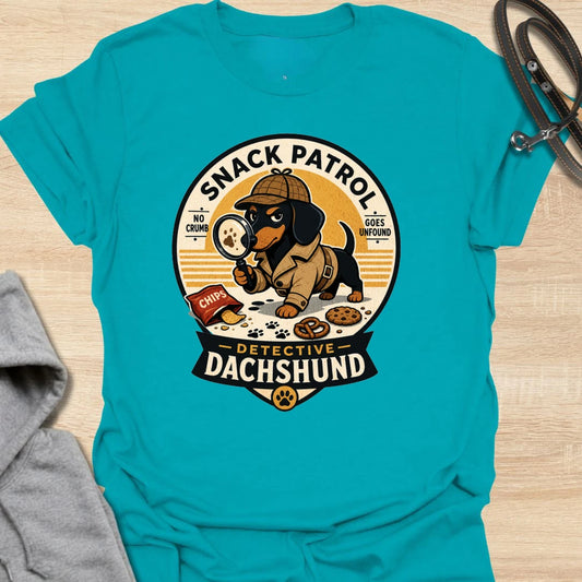 Snack Patrol Detective Dachshund t-shirt for the doxie who is always first on the scene when food appears. This funny badge-style design features a dachshund detective theme with snack details and retro lettering. It is perfect for dachshund owners whose dog monitors every bite, crumb, and kitchen sound. A great gift for wiener dog lovers, sausage dog fans, and food-motivated dog households.