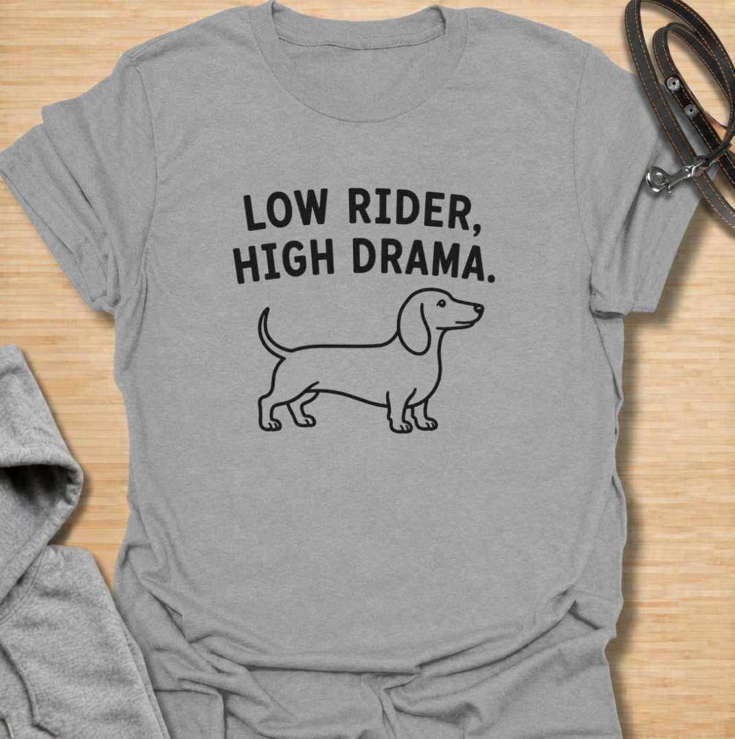 Low to the ground and never short on drama. This funny dachshund T-shirt features a clean minimalist sausage dog illustration with the phrase “Low Rider, High Drama.” A simple, wearable gift for dachshund owners, doxie lovers, dog moms, and anyone familiar with the breed’s larger-than-life personality.