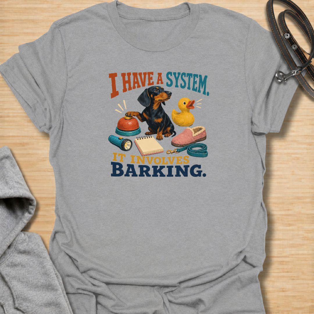 Every dachshund has a system—and it usually involves barking. This funny dachshund T-shirt features a determined sausage dog surrounded by its essential barking equipment, making it perfect for doxie owners who know the routine. A playful everyday tee and a fun gift for dachshund moms, dads, and devoted dog lovers.