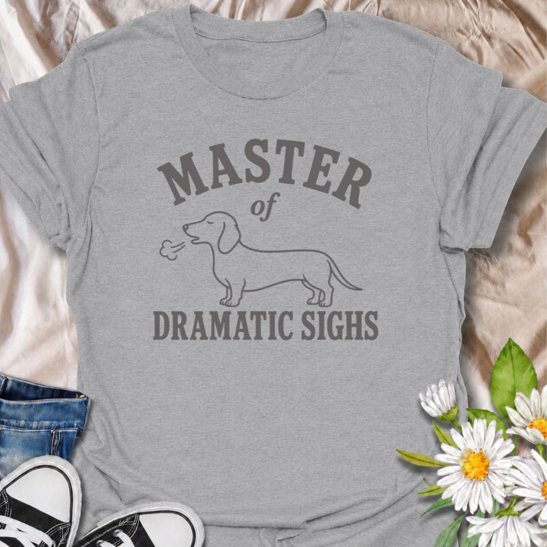 For the dachshund who turns every minor inconvenience into a full performance. This funny dachshund T-shirt features a simple sausage dog illustration with the phrase “Master of Dramatic Sighs.” A playful, easy-to-wear gift for dachshund owners, dog moms, dog dads, and anyone familiar with classic doxie drama.