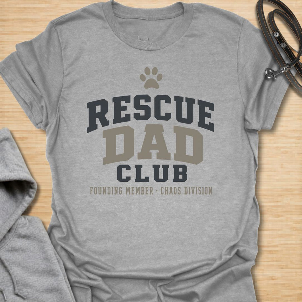 This Rescue Dad Club t-shirt is made for proud dog dads who know rescue dogs bring love, loyalty, and just the right amount of chaos. Featuring bold varsity-style lettering, a paw print, bone accents, and the phrase founding member chaos division, this design has a clean sporty look with a funny rescue-dog twist. Perfect for rescue dog dads, foster dog dads, shelter dog adopters, dog lovers, and anyone proudly raising a second-chance pup.