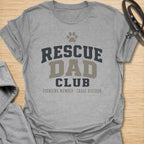 This Rescue Dad Club t-shirt is made for proud dog dads who know rescue dogs bring love, loyalty, and just the right amount of chaos. Featuring bold varsity-style lettering, a paw print, bone accents, and the phrase founding member chaos division, this design has a clean sporty look with a funny rescue-dog twist. Perfect for rescue dog dads, foster dog dads, shelter dog adopters, dog lovers, and anyone proudly raising a second-chance pup.