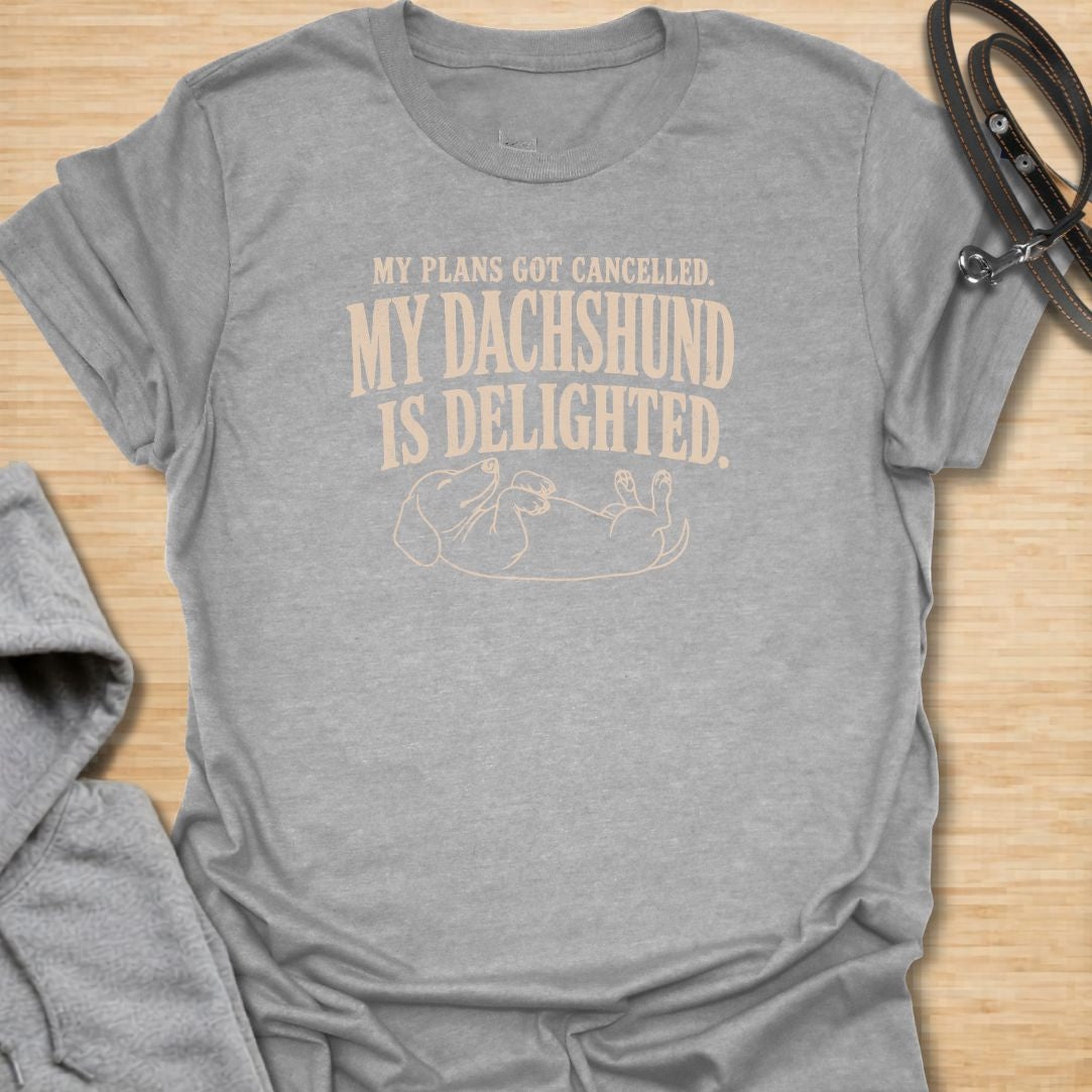 This My Plans Got Canceled My Dachshund Is Delighted t-shirt is made for doxie lovers who know their little long dog is happiest when everyone stays home. Featuring bold vintage-style typography and a relaxed dachshund lying on its back, this design has a funny, relatable dog-parent feel that wiener dog fans will instantly understand. Perfect for dachshund moms, dachshund dads, rescue dog lovers, introverts, and anyone whose dachshund fully supports canceled plans.