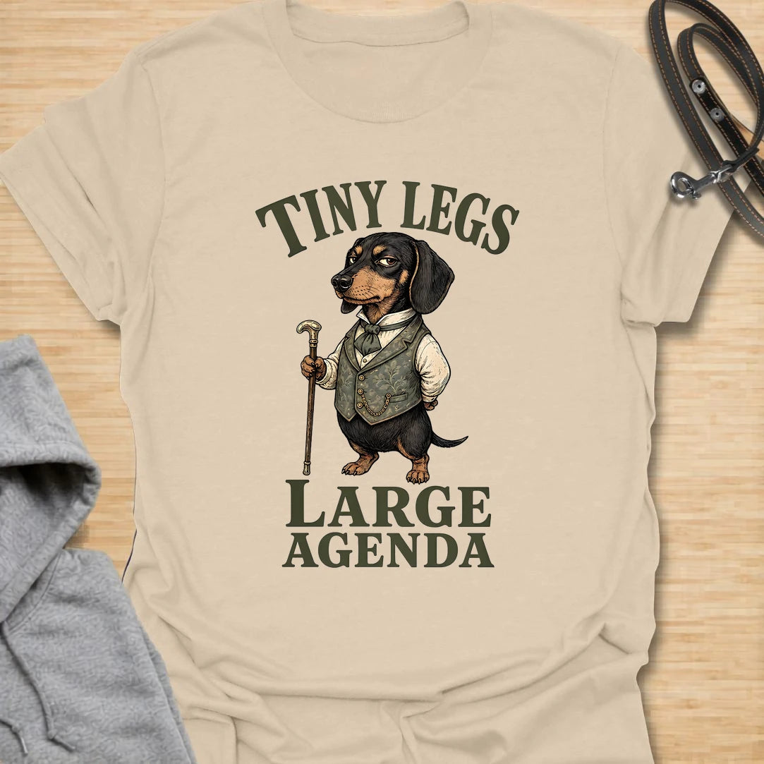 This Tiny Legs Large Agenda t-shirt is made for dachshund lovers who know their little long dog has plans, opinions, and absolutely no time to waste. Featuring a dressed-up dachshund with a cane and bold vintage-style lettering, this design has a funny, dramatic dog-parent feel. Perfect for dachshund moms, dachshund dads, wiener dog fans, rescue dog lovers, and anyone whose tiny-legged dog has big plans.