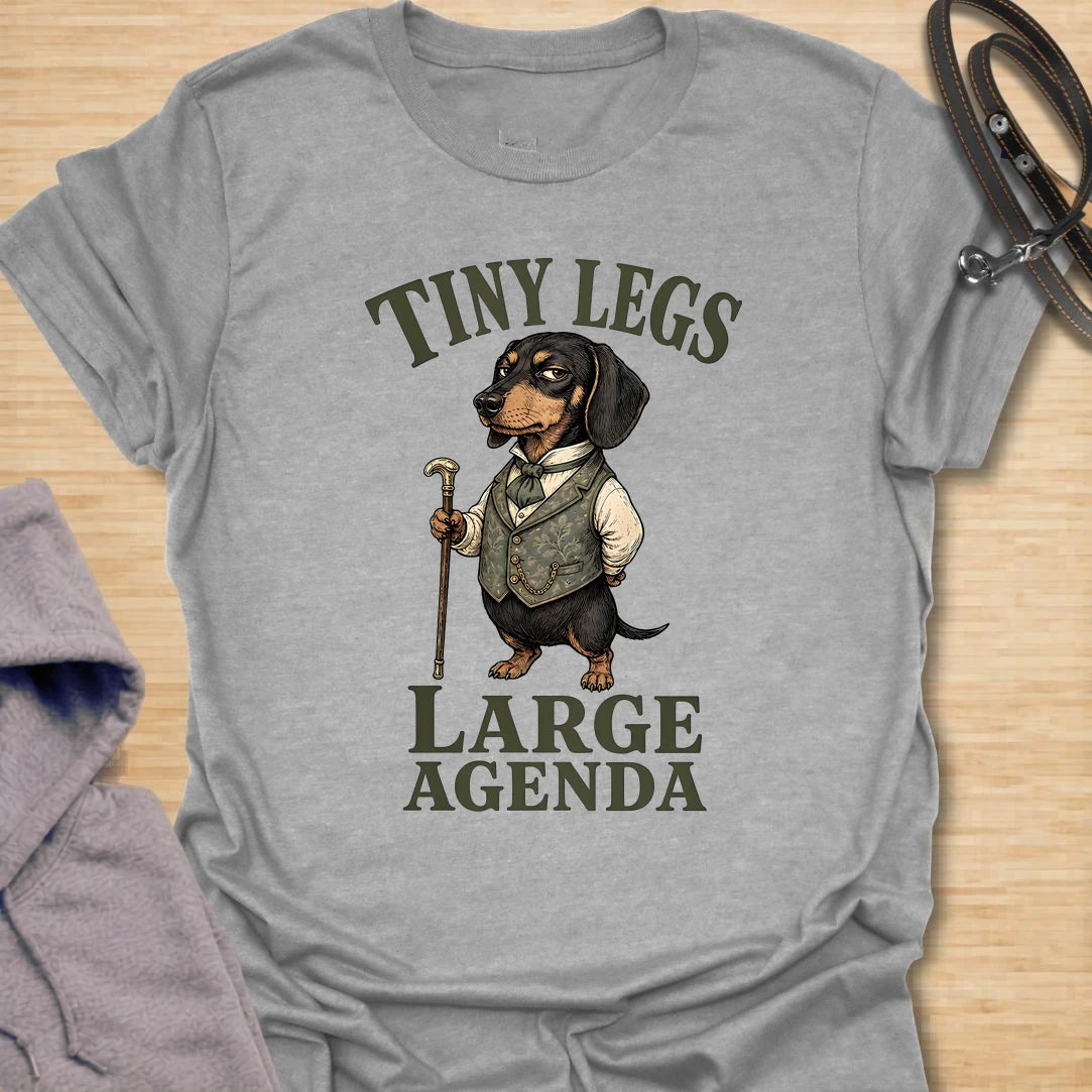 This Tiny Legs Large Agenda t-shirt is made for dachshund lovers who know their little long dog has plans, opinions, and absolutely no time to waste. Featuring a dressed-up dachshund with a cane and bold vintage-style lettering, this design has a funny, dramatic dog-parent feel. Perfect for dachshund moms, dachshund dads, wiener dog fans, rescue dog lovers, and anyone whose tiny-legged dog has big plans.