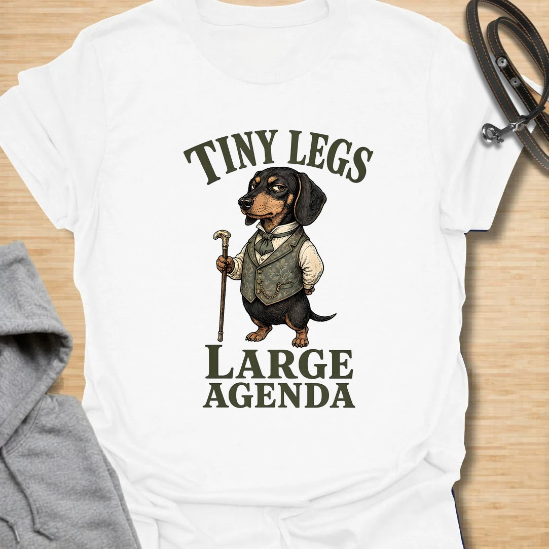 This Tiny Legs Large Agenda t-shirt is made for dachshund lovers who know their little long dog has plans, opinions, and absolutely no time to waste. Featuring a dressed-up dachshund with a cane and bold vintage-style lettering, this design has a funny, dramatic dog-parent feel. Perfect for dachshund moms, dachshund dads, wiener dog fans, rescue dog lovers, and anyone whose tiny-legged dog has big plans.
