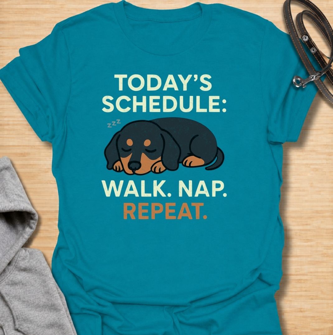 A funny dachshund T-shirt for anyone familiar with the very demanding daily routine of a sausage dog. Featuring the phrase “Today’s Schedule: Walk. Nap. Repeat.” with a sleepy dachshund illustration, this design captures the breed’s love of short adventures followed by serious rest. Perfect for dachshund moms, dachshund dads, wiener dog owners, and anyone whose dog has mastered the art of doing just enough. A playful everyday tee for fans of dachshund humor, lazy dog jokes, and breed-specific gifts.