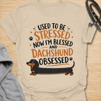 This Used To Be Stressed Now I’m Blessed And Dachshund Obsessed t-shirt is made for dachshund lovers who know life got a whole lot better with a sausage dog in it. Featuring playful stacked typography, a long dachshund illustration, and a fun feel-good message, this design has a cheerful and relatable dog-lover vibe. Perfect for dachshund moms, dachshund dads, wiener dog fans, doxie owners, and anyone who proudly admits they are completely dachshund obsessed.
