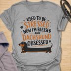This Used To Be Stressed Now I’m Blessed And Dachshund Obsessed t-shirt is made for dachshund lovers who know life got a whole lot better with a sausage dog in it. Featuring playful stacked typography, a long dachshund illustration, and a fun feel-good message, this design has a cheerful and relatable dog-lover vibe. Perfect for dachshund moms, dachshund dads, wiener dog fans, doxie owners, and anyone who proudly admits they are completely dachshund obsessed.