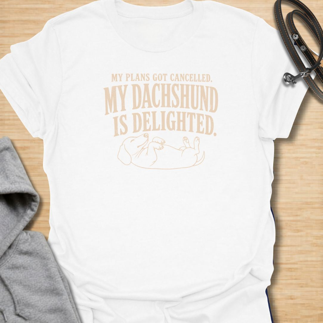 This My Plans Got Canceled My Dachshund Is Delighted t-shirt is made for doxie lovers who know their little long dog is happiest when everyone stays home. Featuring bold vintage-style typography and a relaxed dachshund lying on its back, this design has a funny, relatable dog-parent feel that wiener dog fans will instantly understand. Perfect for dachshund moms, dachshund dads, rescue dog lovers, introverts, and anyone whose dachshund fully supports canceled plans.